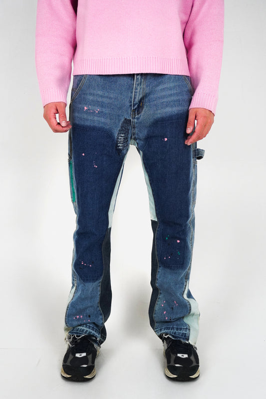 Person wearing a pink sweater and blue jeans with patches on a white background
