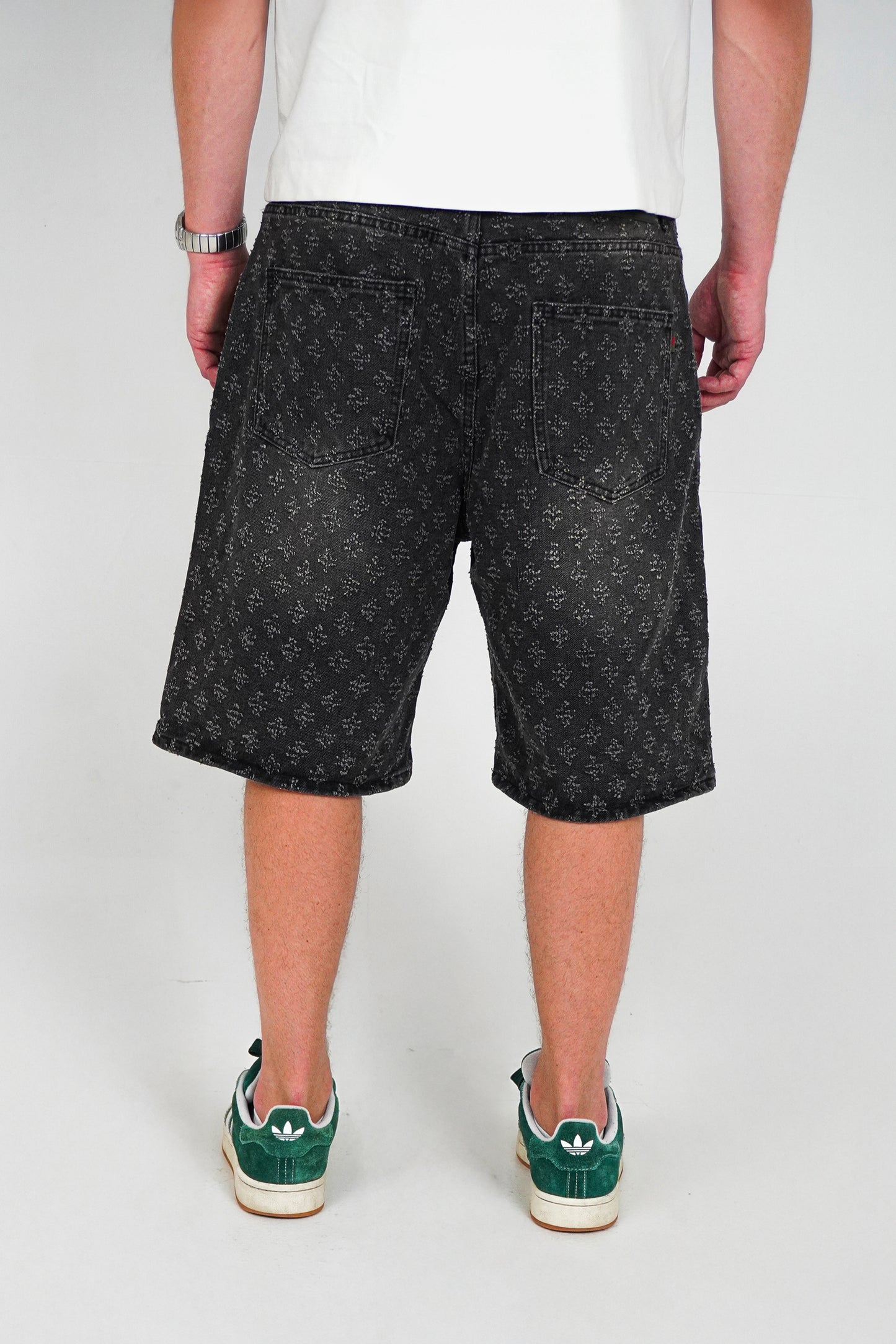 Person wearing black patterned shorts on a white background