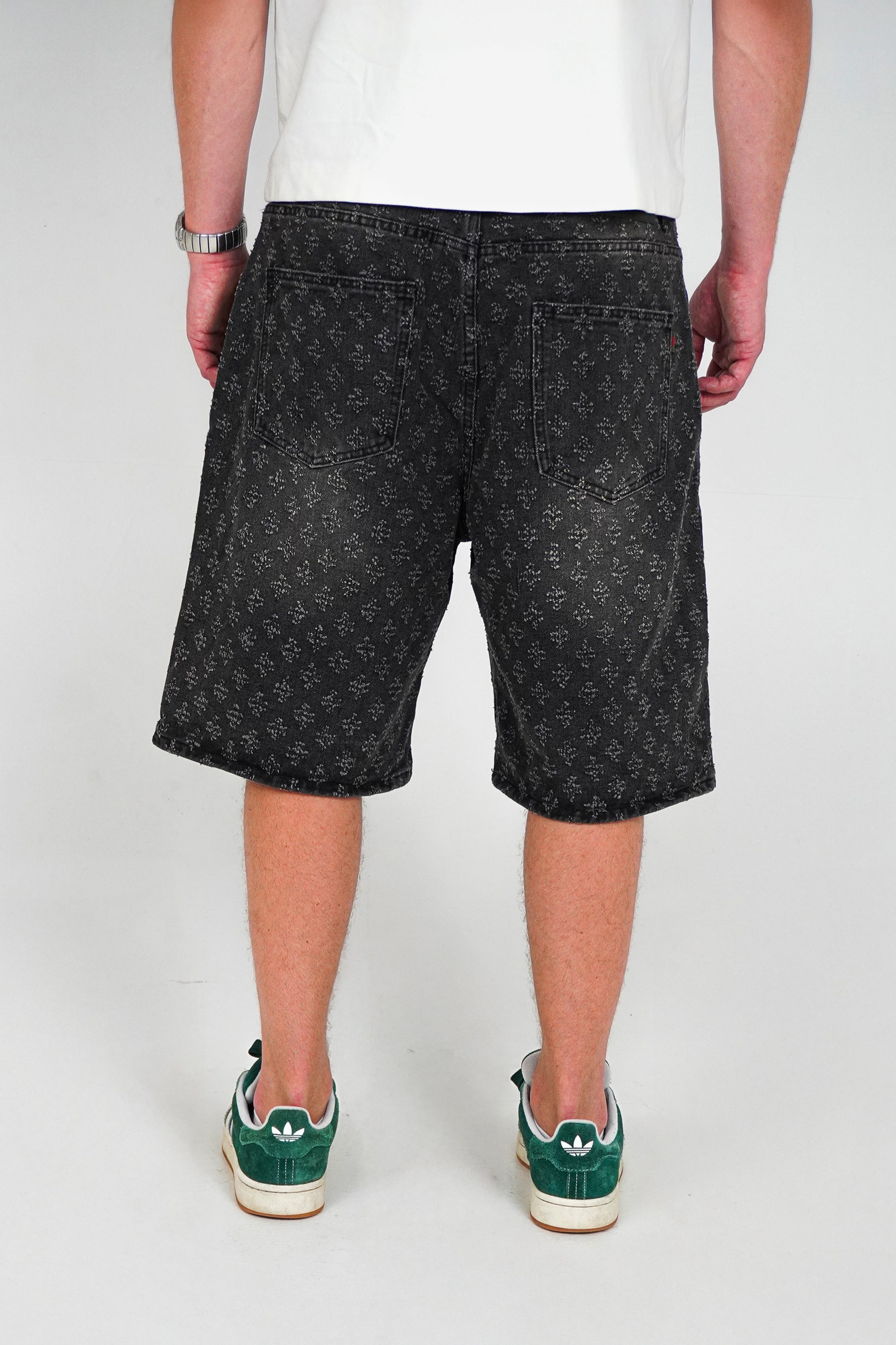 Person wearing black patterned shorts on a white background