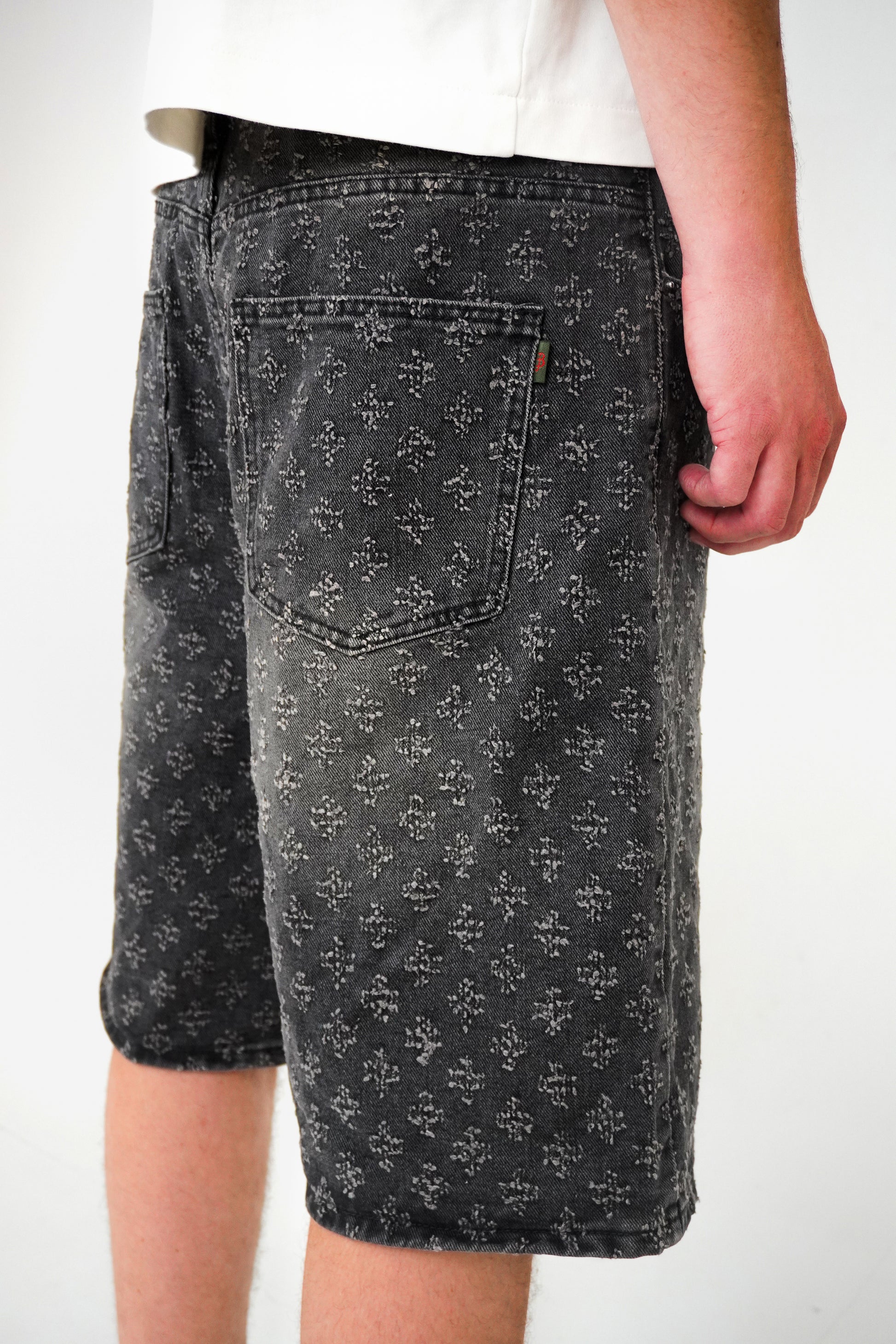 Person wearing black distressed shorts on a white background