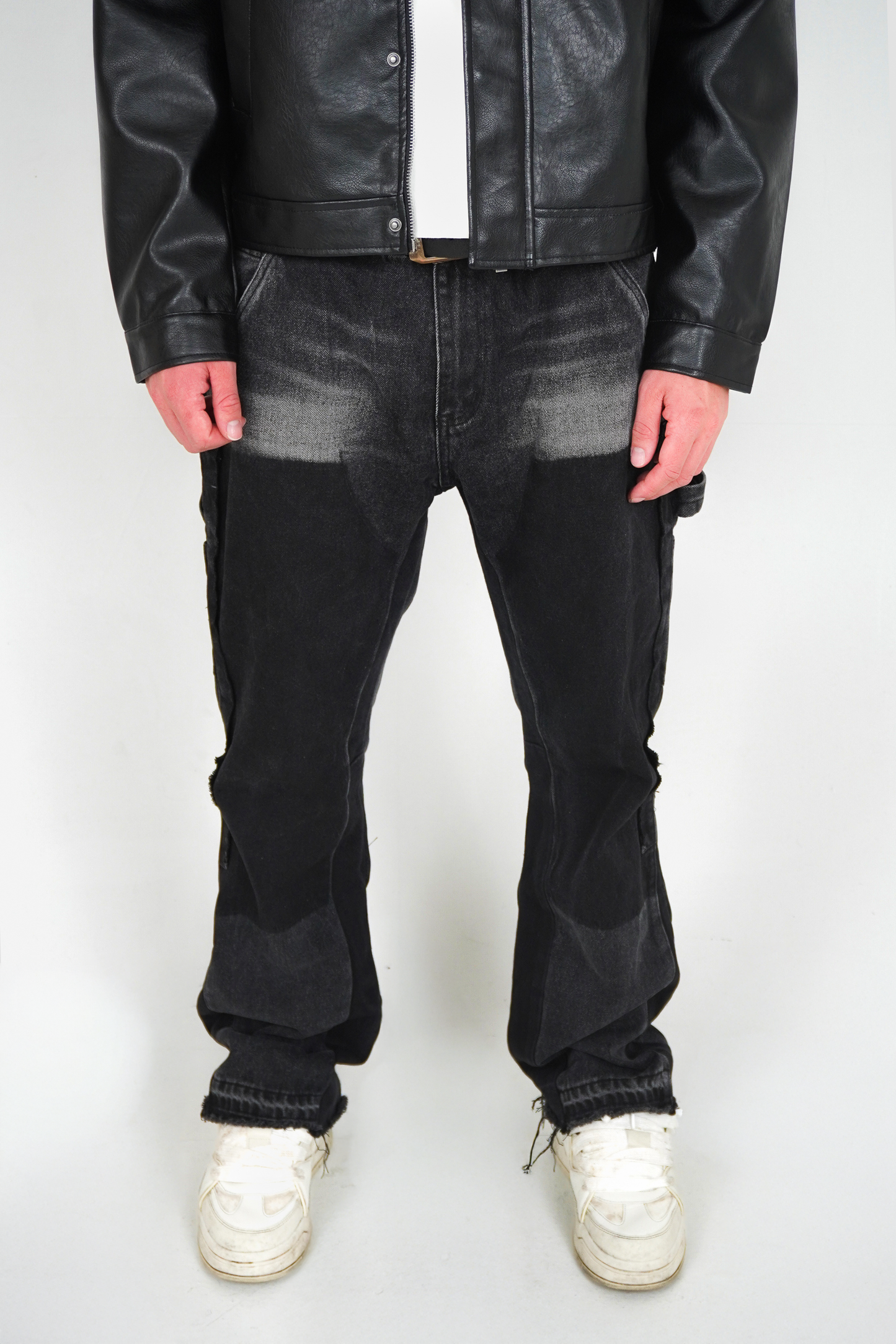 Person wearing a black leather jacket, black jeans, and white sneakers on a white background