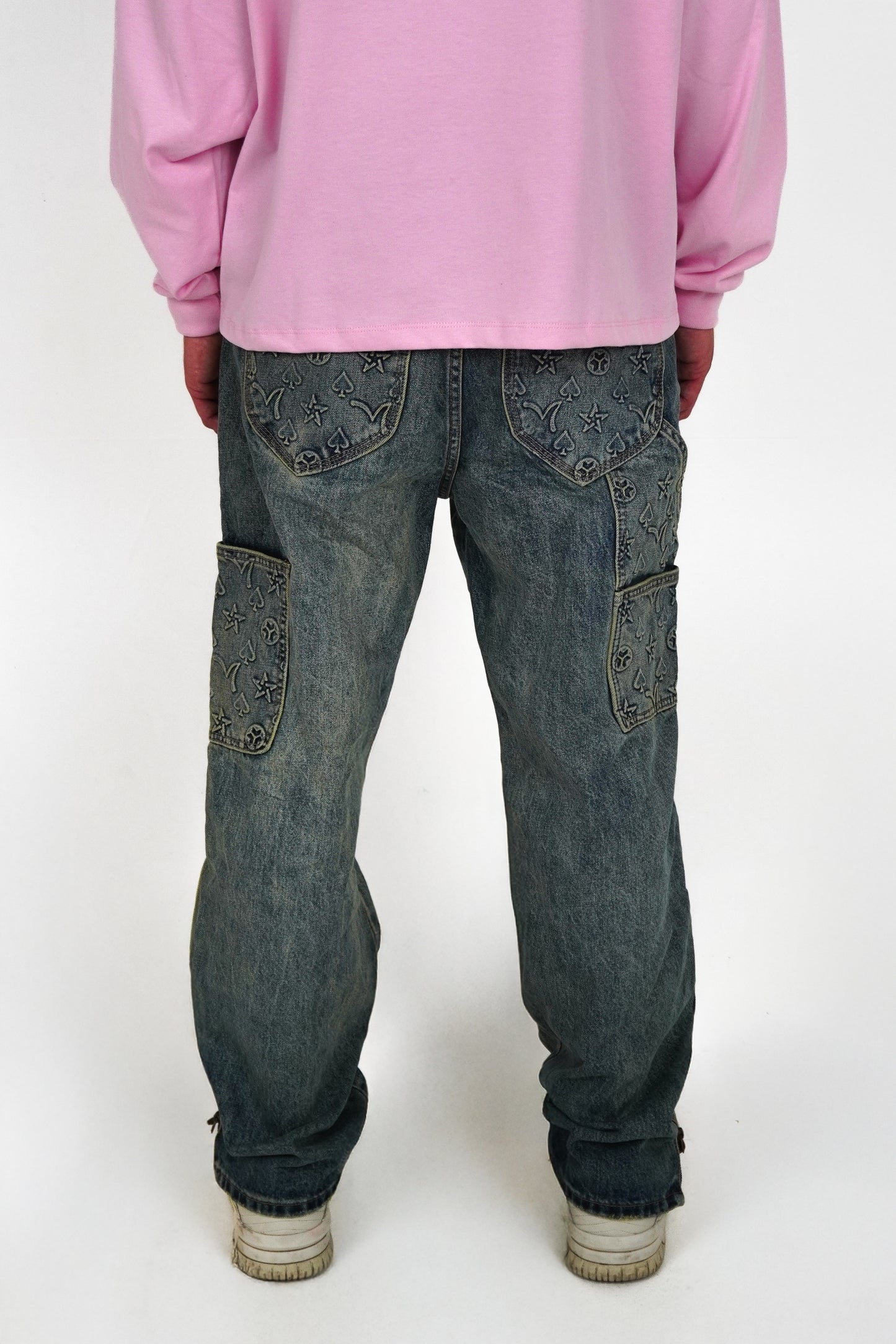 Person wearing a pink sweatshirt and blue jeans on a white background