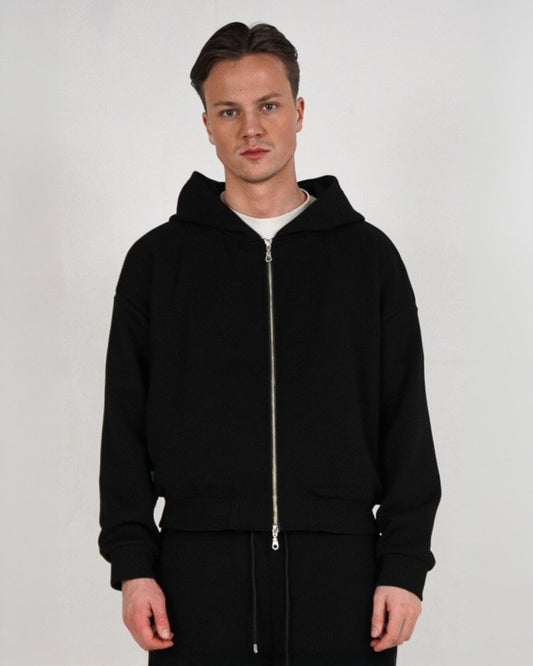 Person wearing a black zip-up hoodie with a white t-shirt underneath.