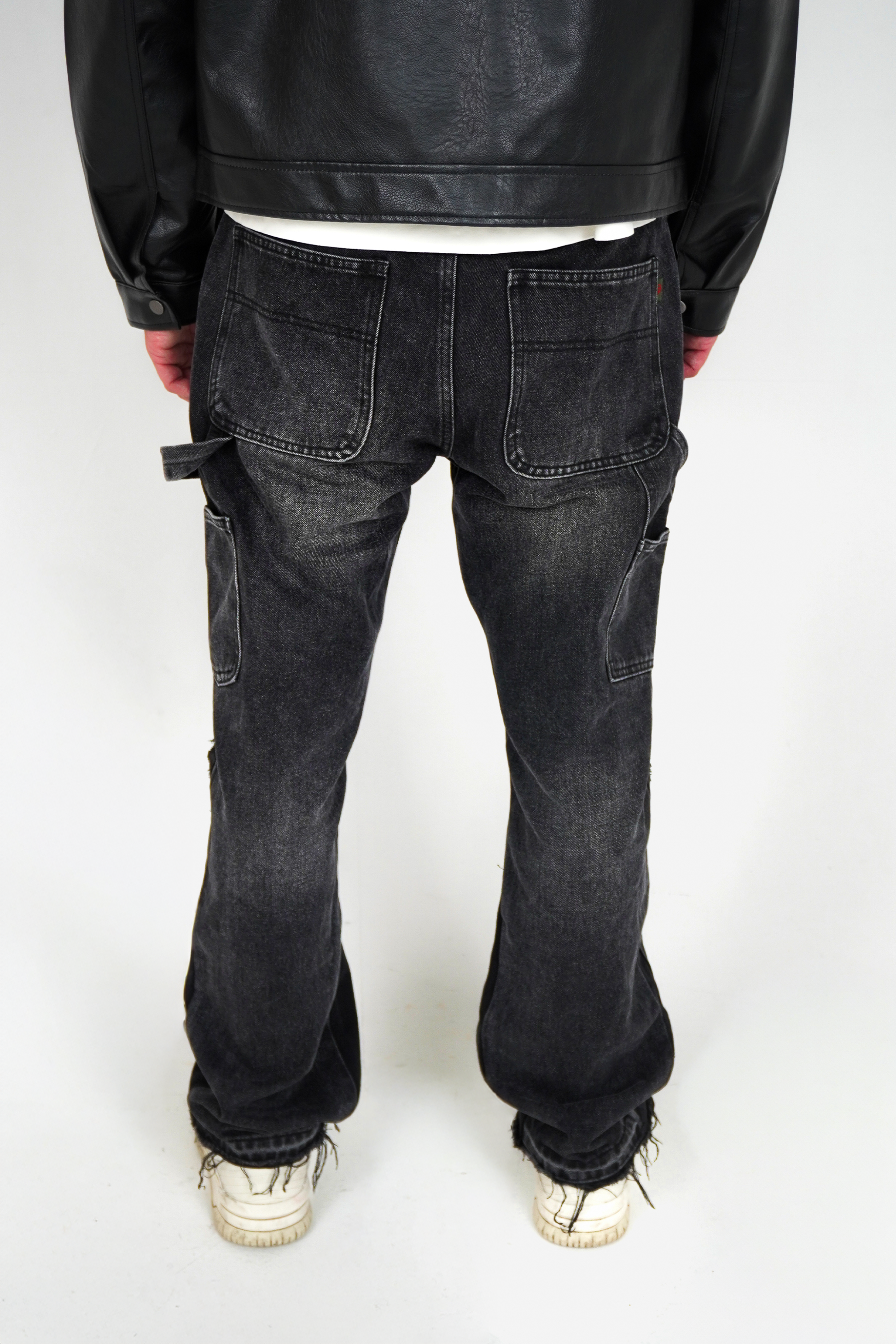 Person wearing black leather jacket and dark jeans on a white background