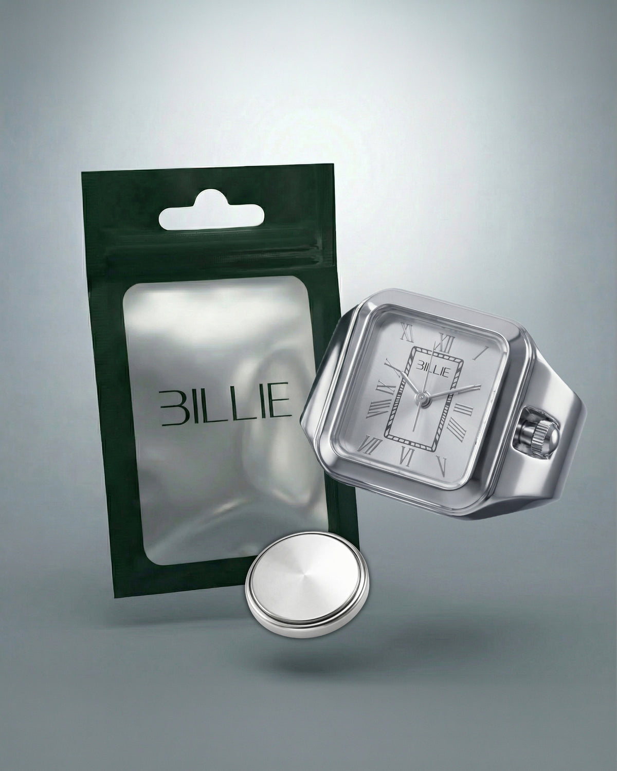 Billie Edge Ring Watch in silver next to its Billie pouch packaging and spare battery