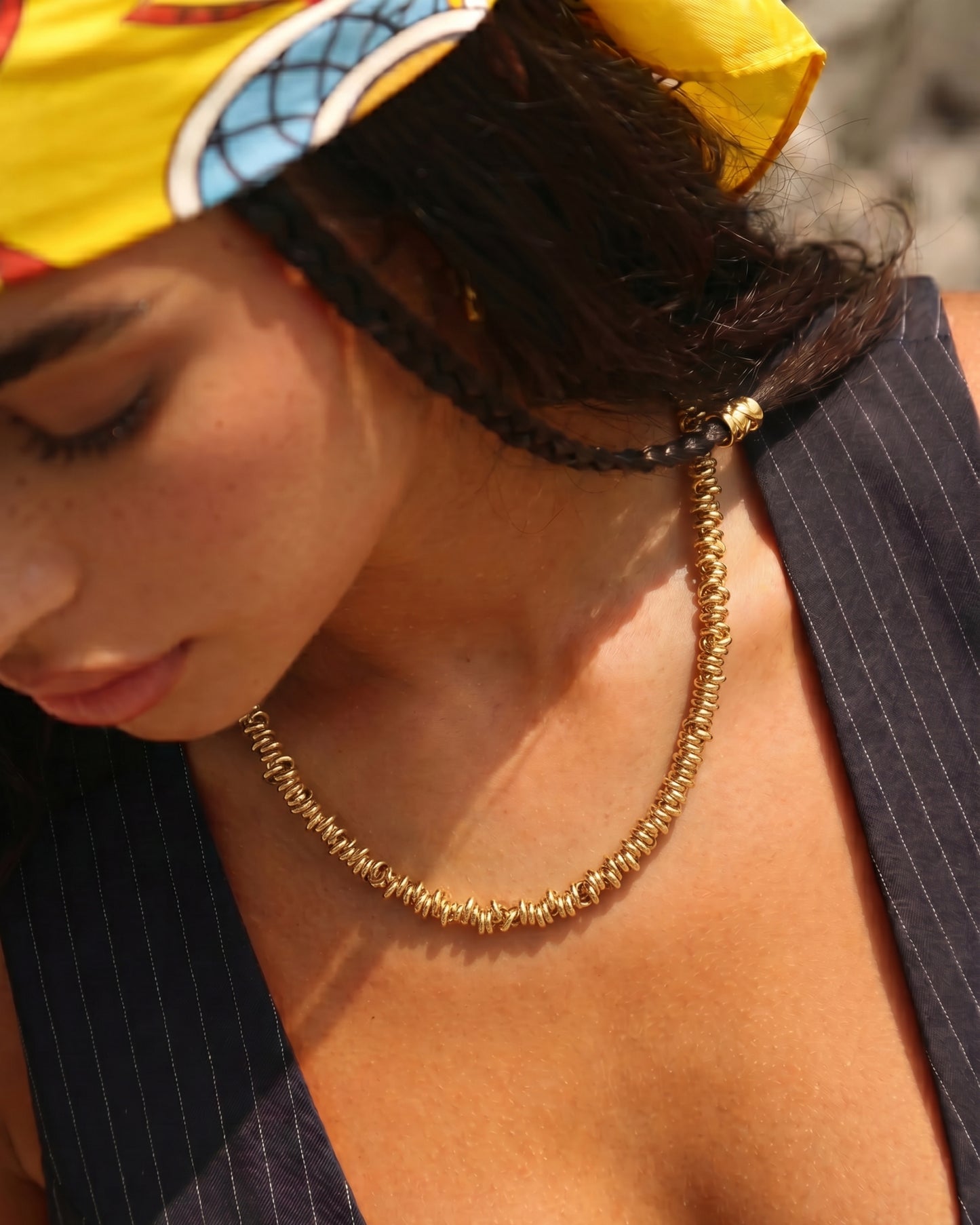 Close-up of a person wearing a gold necklace and a colorful headscarf.