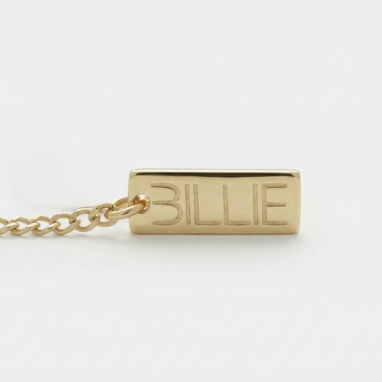 Gold necklace with a tag engraved with 'BILLIE' on a white background