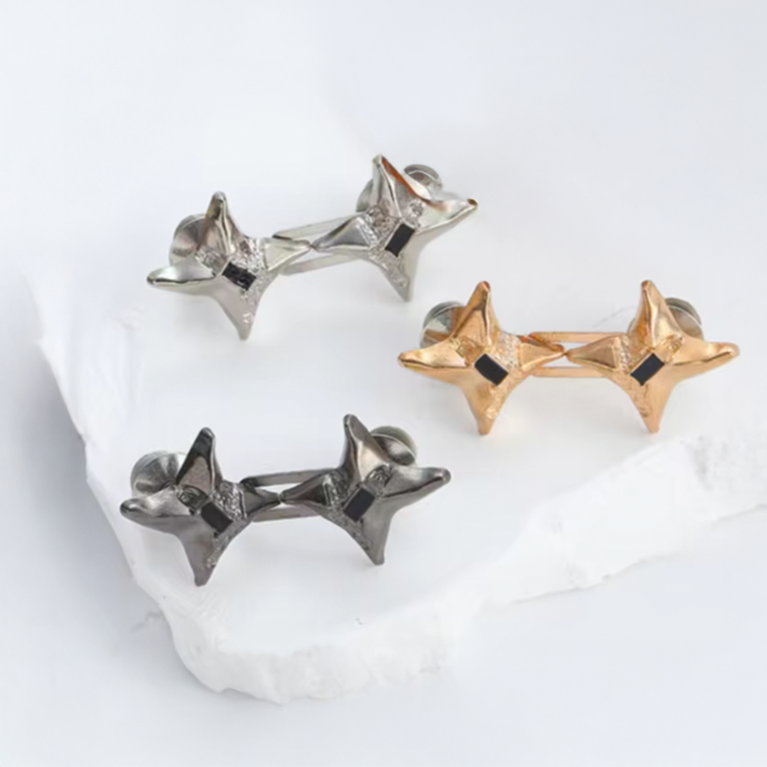 Three pairs of star-shaped waist knots in gold, silver, and black on a white background.