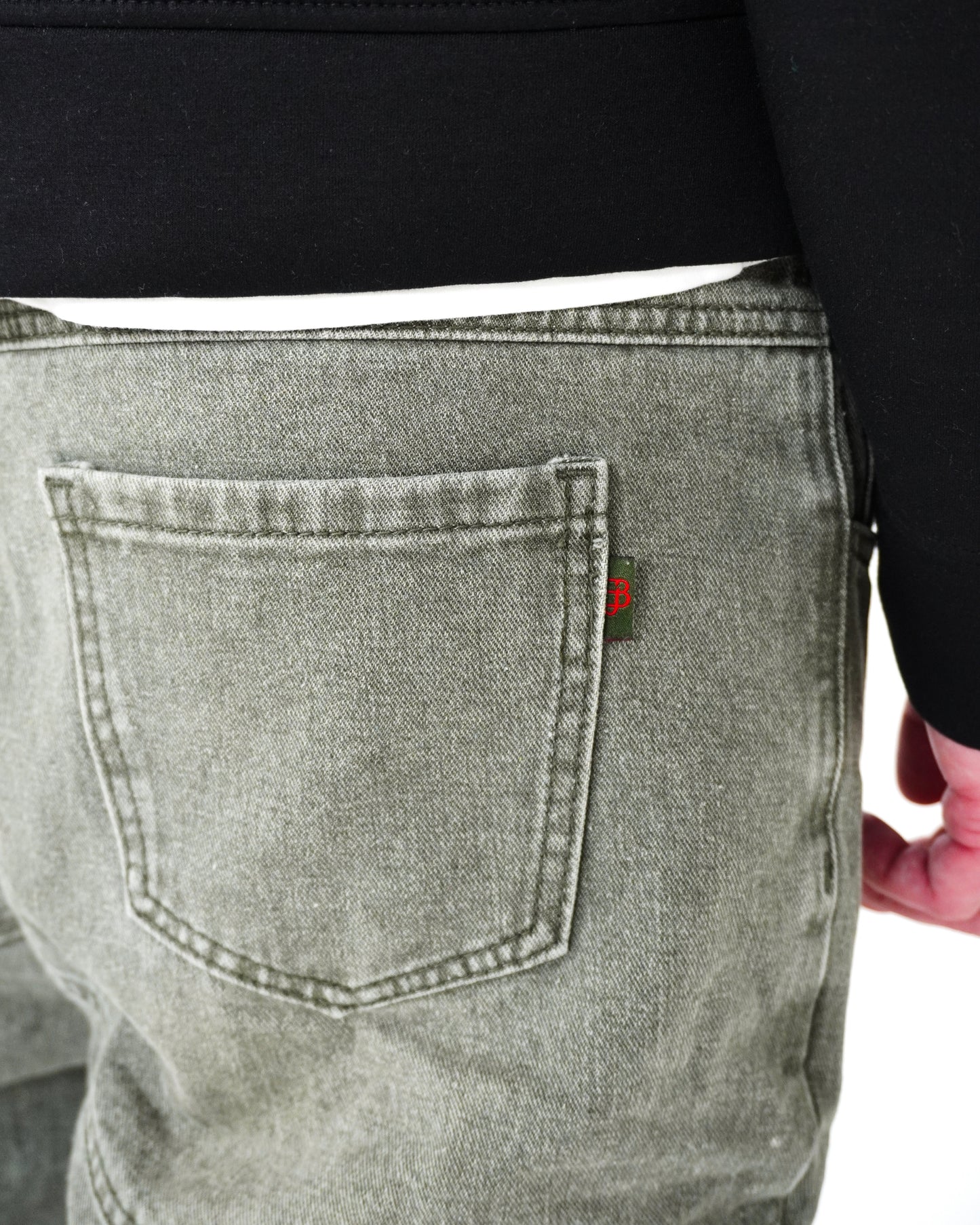 Close-up of back pocket on gray pants with a small red tag.