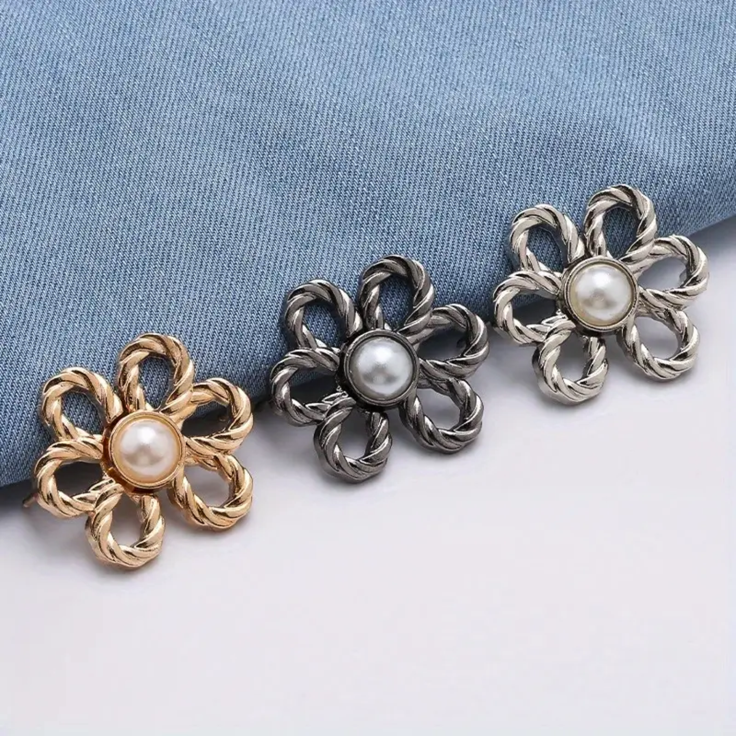 Three waist knotd with pearl centers on a blue fabric background