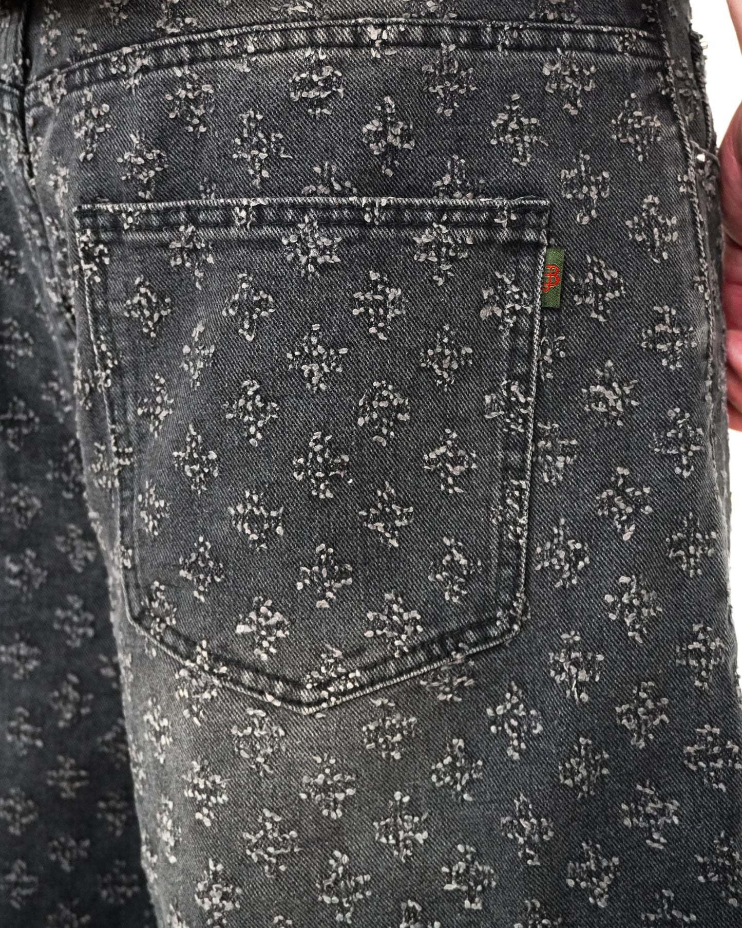 Close-up of a patterned back pocket on dark denim fabric.
