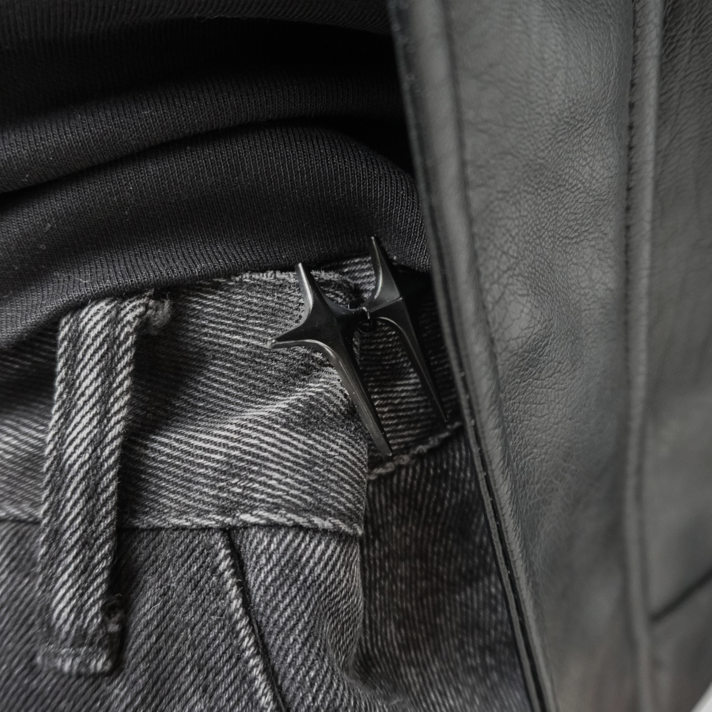 Close-up of a leather jacket with a button and belt buckle detail.