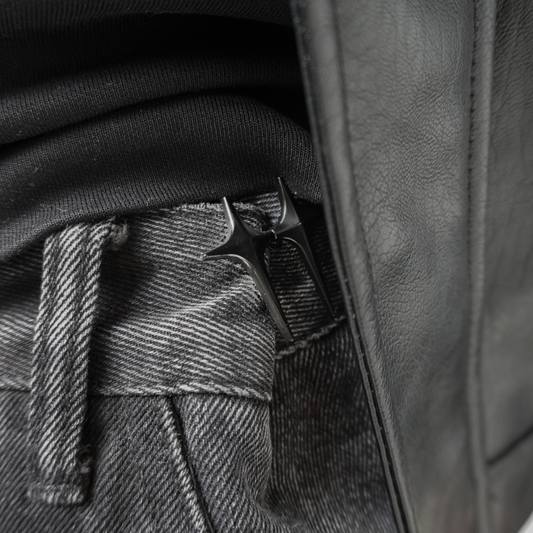 Close-up of a leather jacket with a button and belt buckle detail.