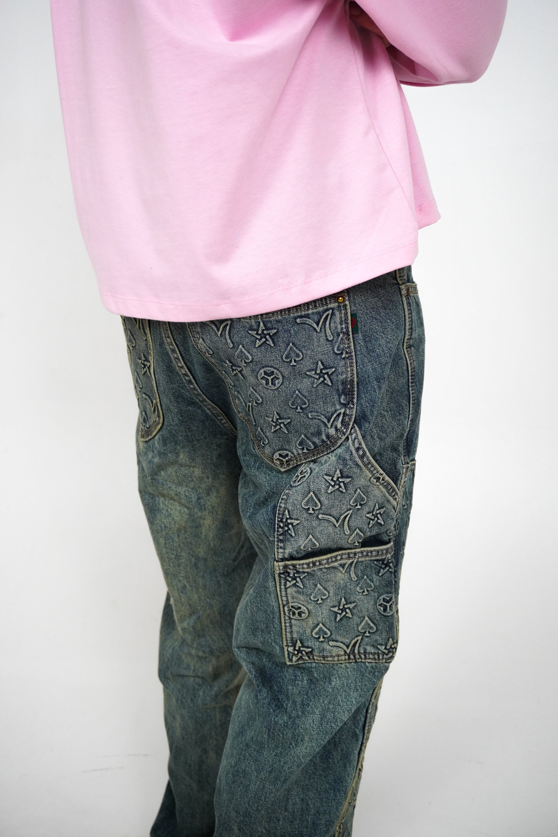 Person wearing pink sweatshirt and blue jeans with star patterns on a white background