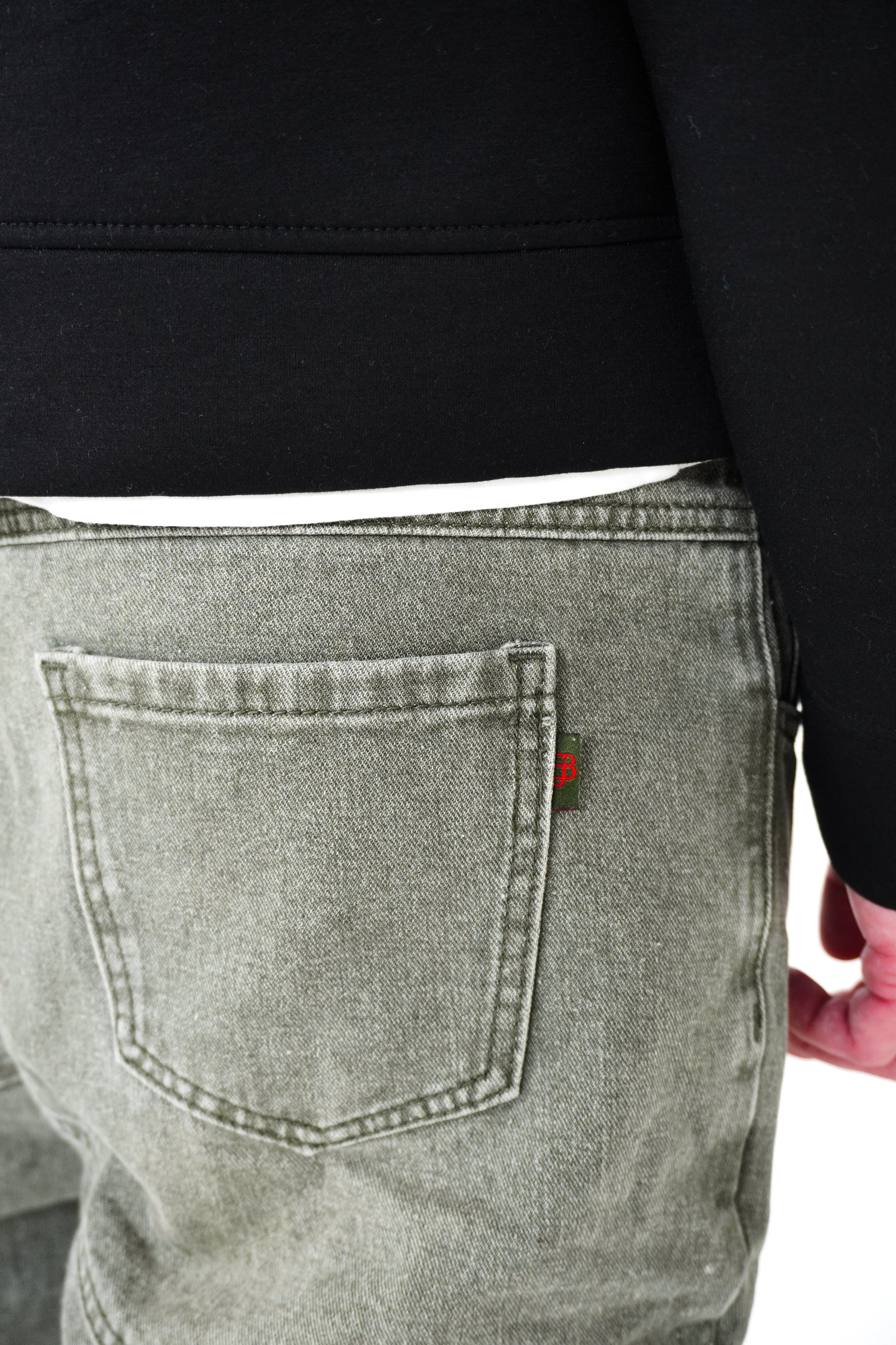 Person wearing green jeans with a brand logo on the back pocket against a white background