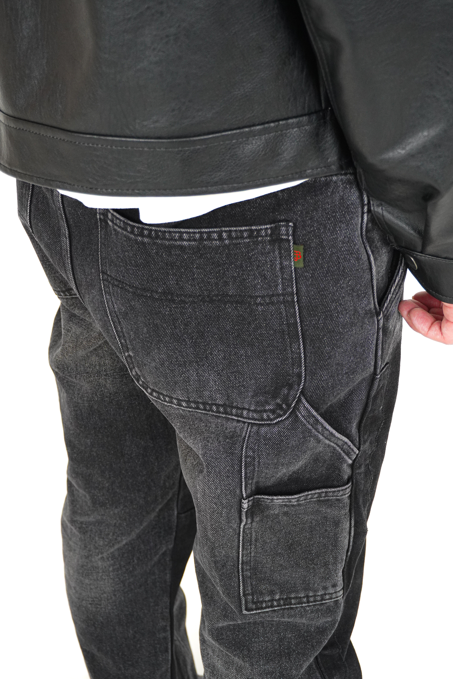 Person wearing black leather jacket and gray cargo pants on a white background