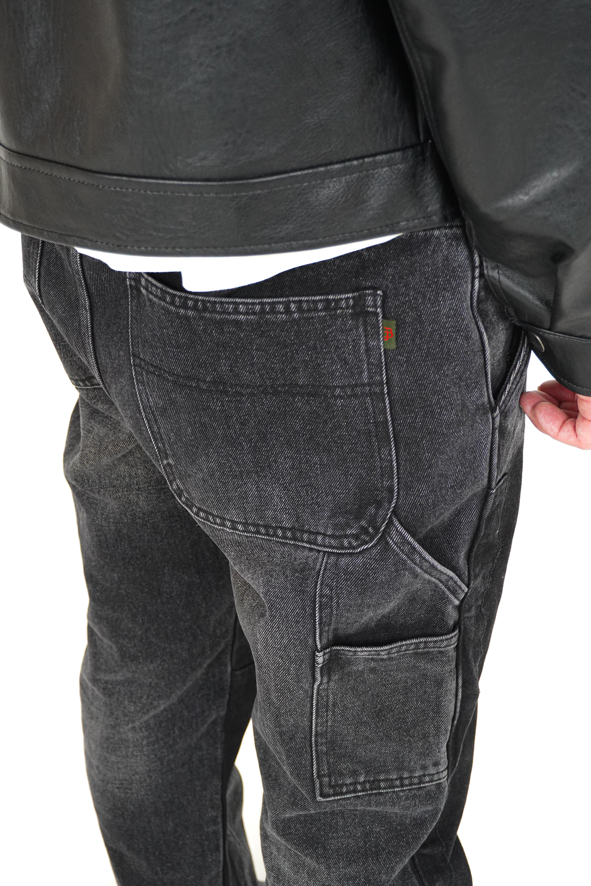 Person wearing black leather jacket and gray cargo pants on a white background