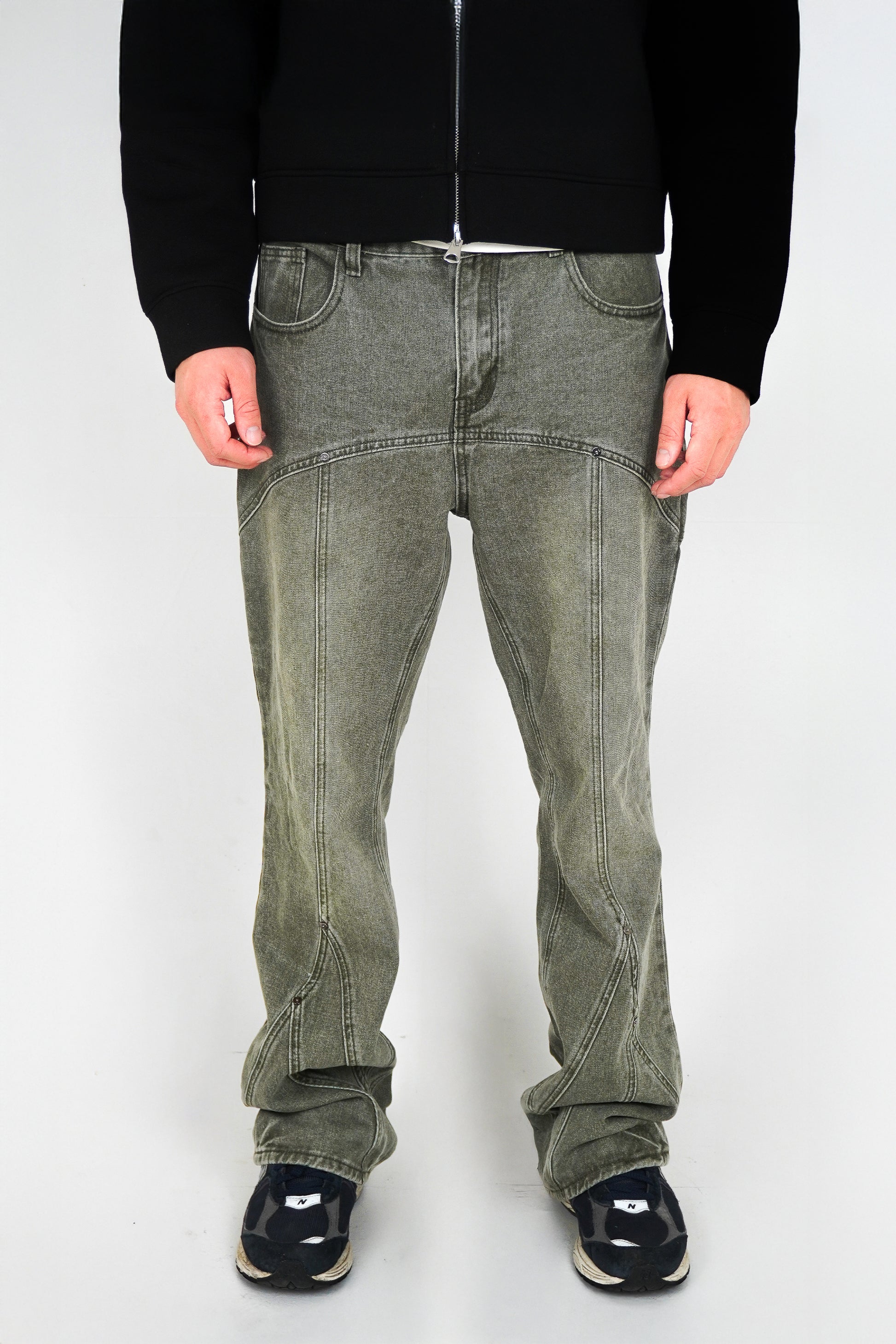 Person wearing green jeans and black shoes on a white background