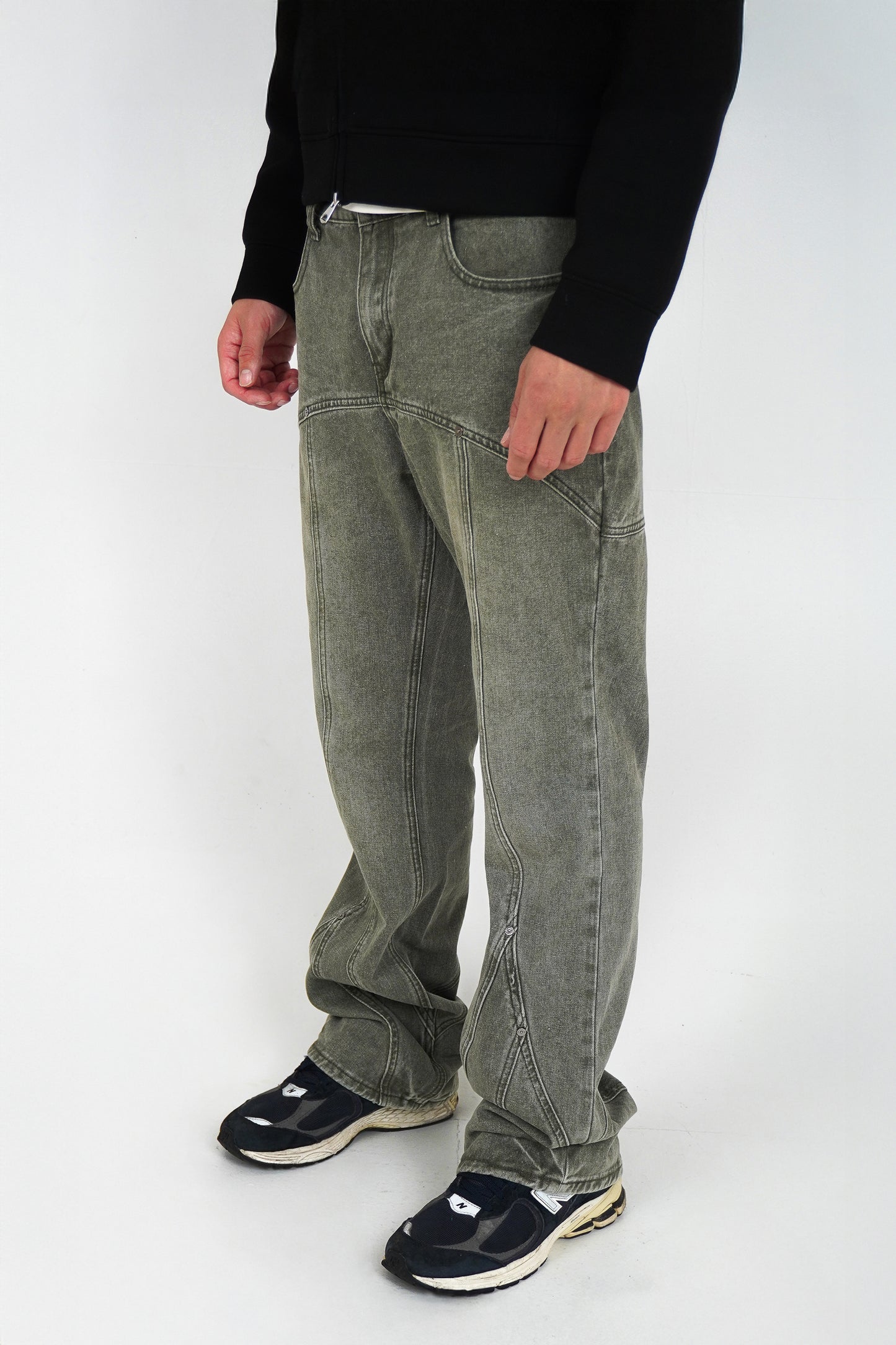 Person wearing flared jeans and black shoes on a white background