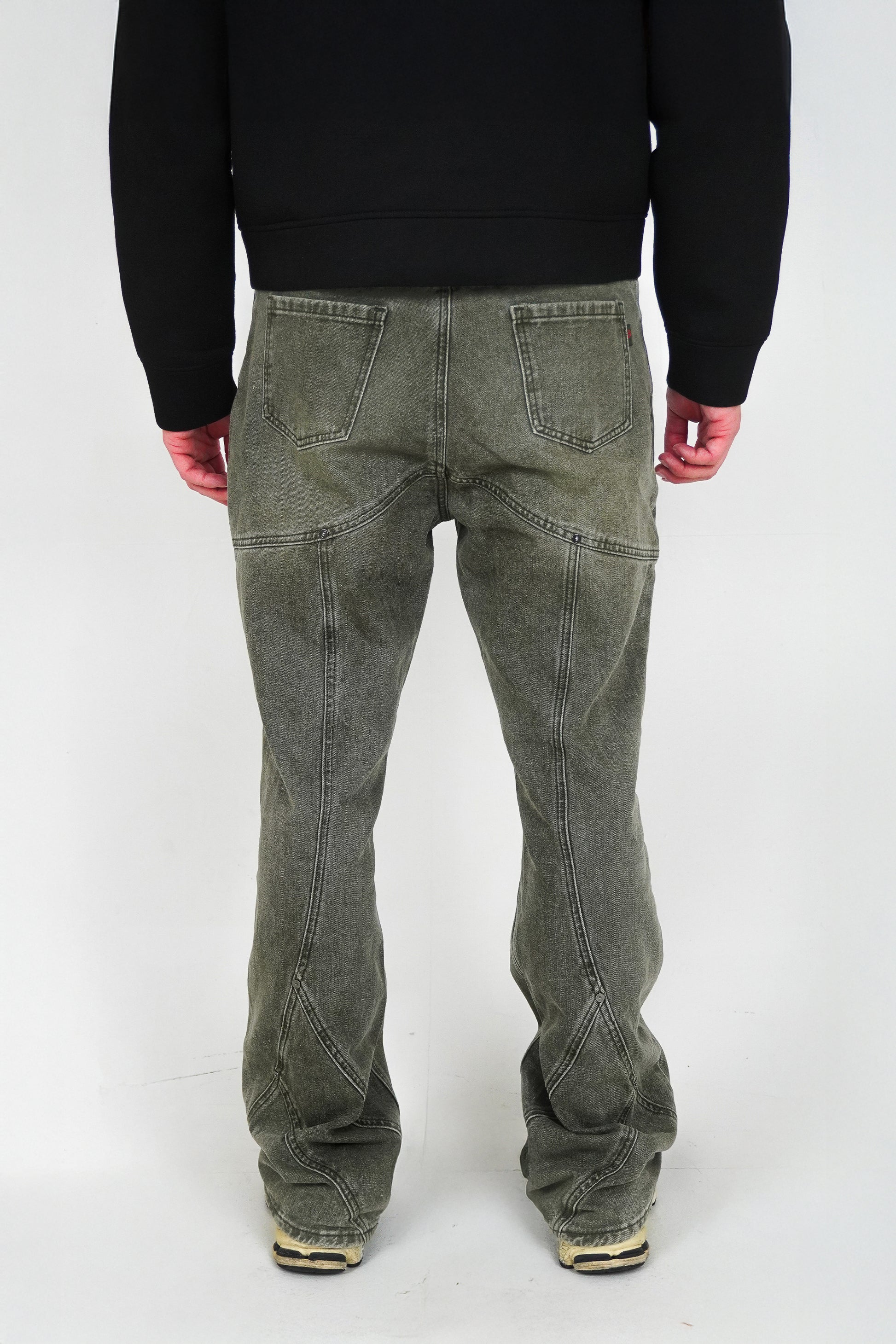 Person wearing green jeans and a black sweater on a white background