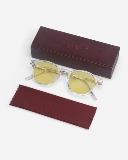 Round yellow-tinted sunglasses on a plain background with a maroon case and cleaning cloth.