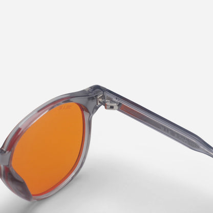 Blue light glasses with orange lenses and transparent frame on a light gray background