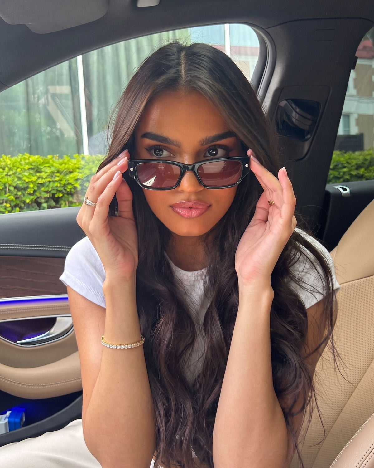 Woman adjusting her sunglasses in a car wearing the gold Billie Tennis Bracelet 4mm and tennis chain