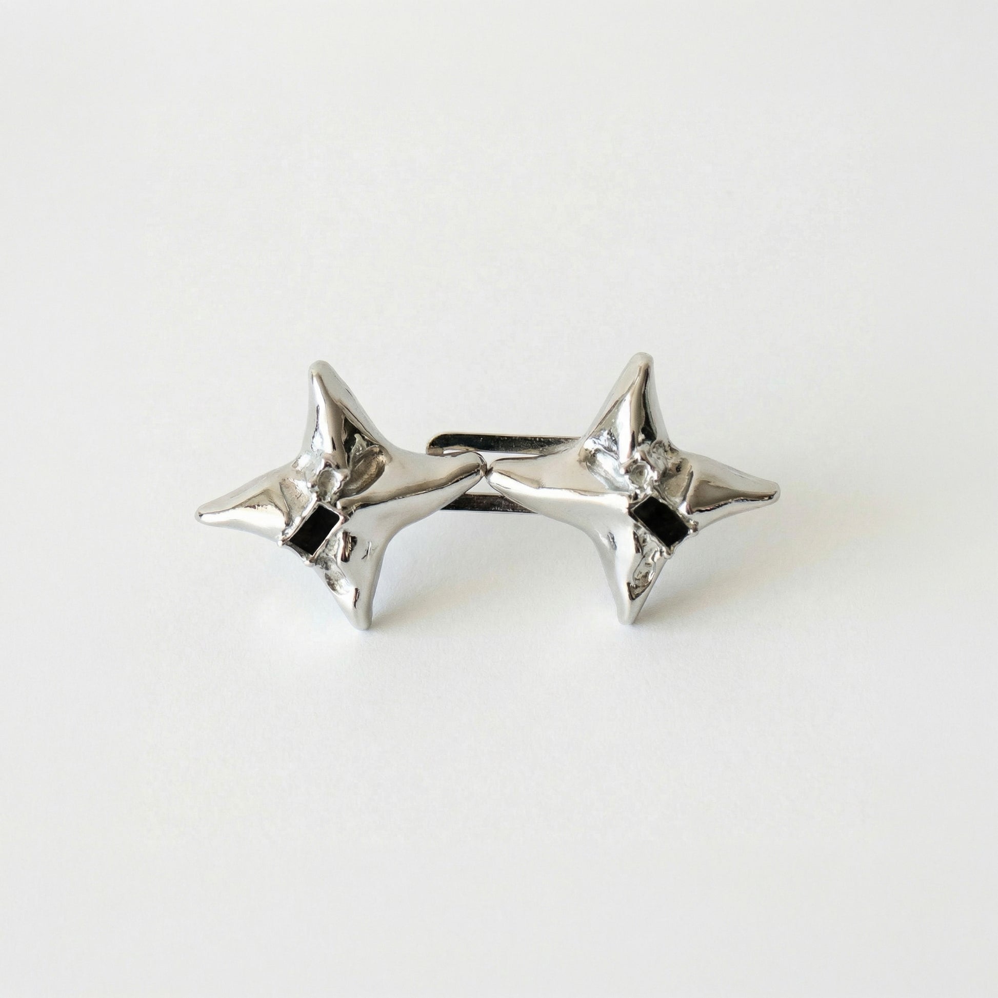 Pair of silver star-shaped earrings on a light gray background