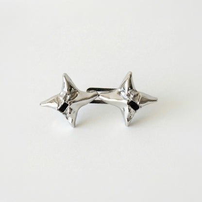 Pair of silver star-shaped earrings on a light gray background