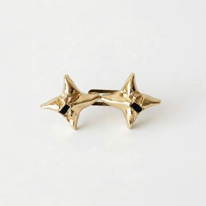 Gold star-shaped earrings with black centers on a white background