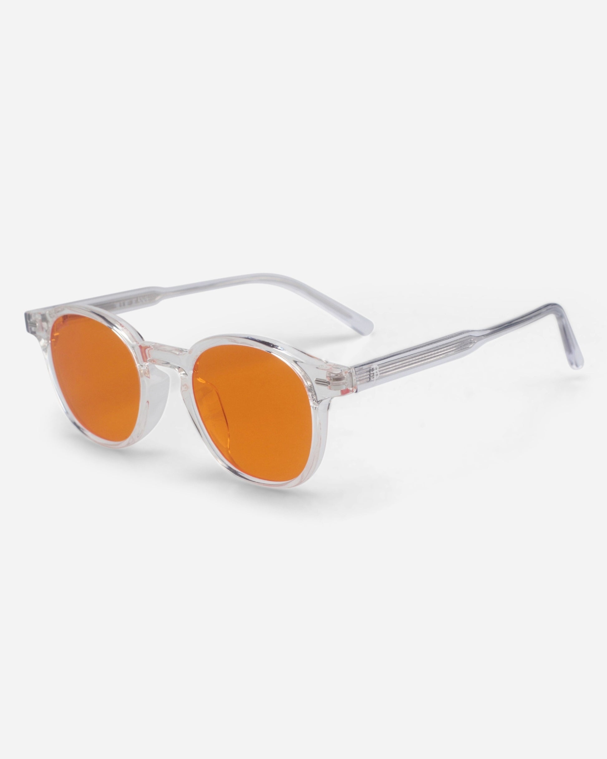Clear frame sunglasses with orange lenses on a plain background