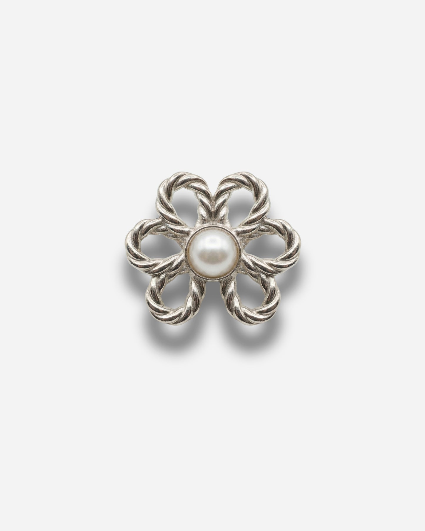 Silver flower-shaped brooch with a central pearl on a plain background.