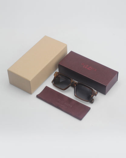 Sunglasses on a plain background with a brown box and a beige box.