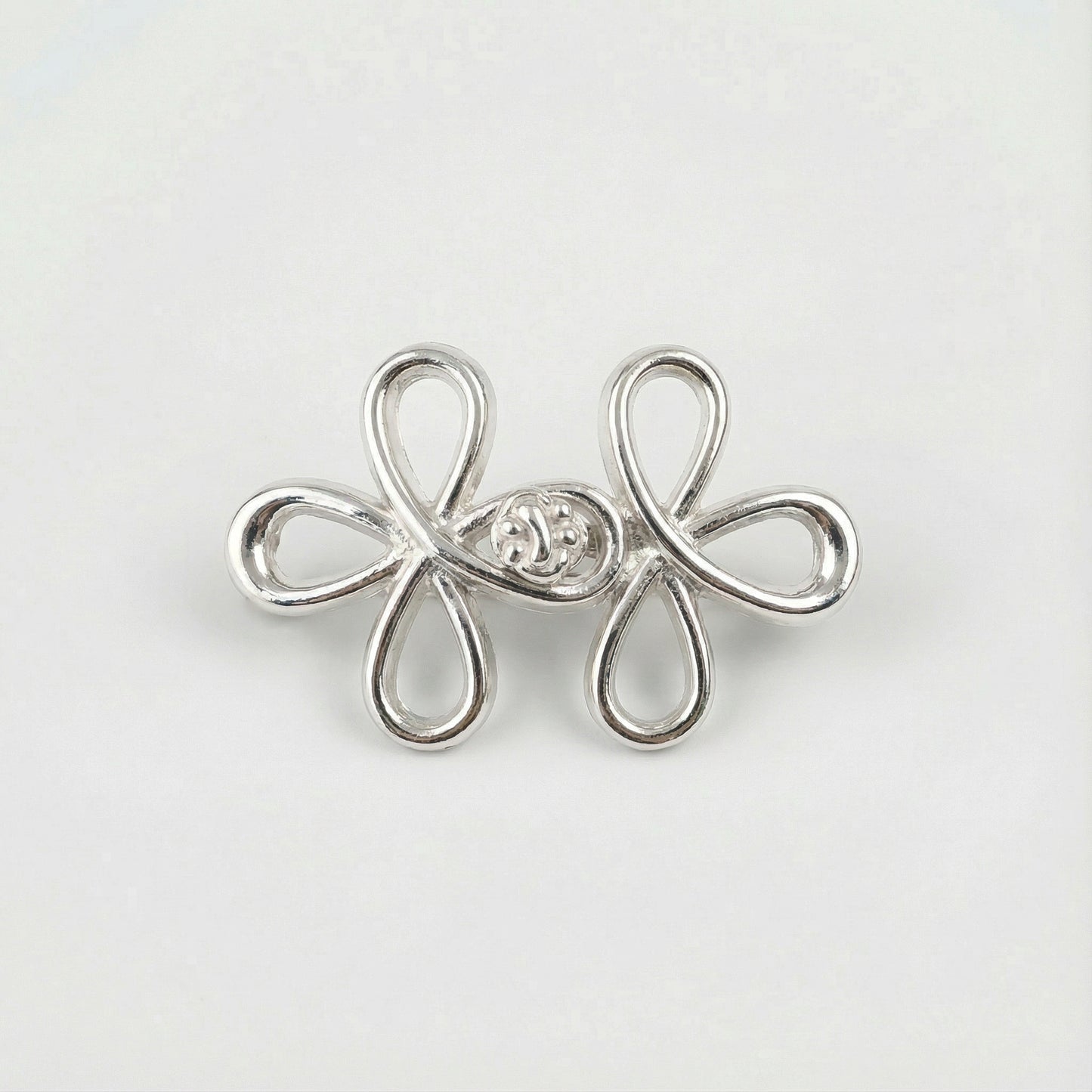 Silver flower-shaped earring with a central gemstone on a light gray background