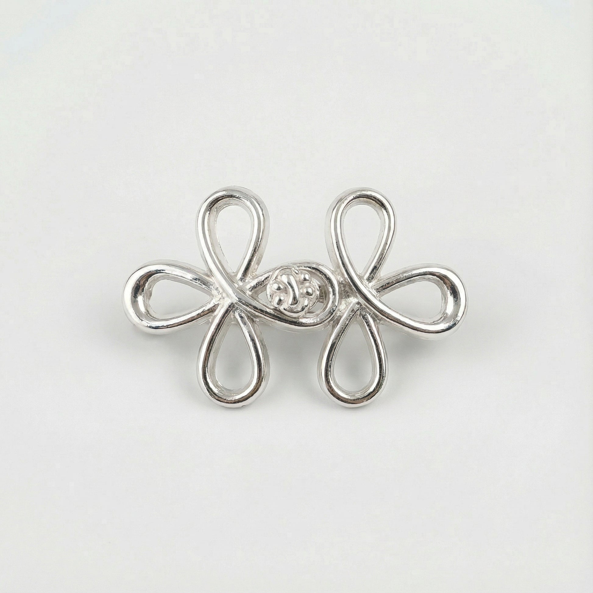 Silver flower-shaped earring with a central gemstone on a light gray background