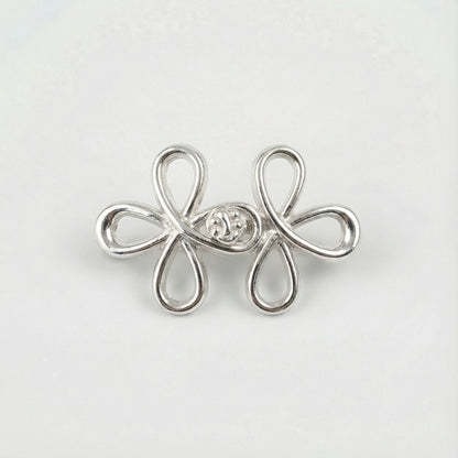 Silver flower-shaped earring with a central gemstone on a light gray background