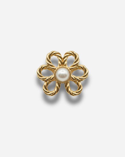 Gold flower-shaped brooch with a pearl center on a plain background.