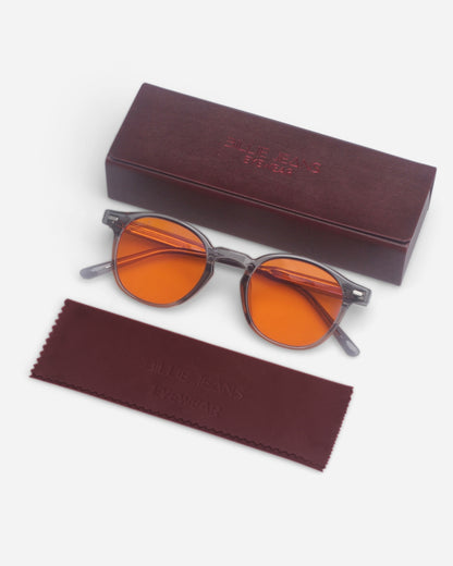 Round sunglasses with orange lenses on a plain background, accompanied by a case and cleaning cloth.