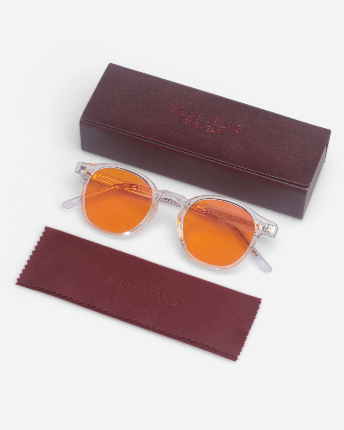 Clear sunglasses with orange lenses, cleaning cloth, and a maroon box.