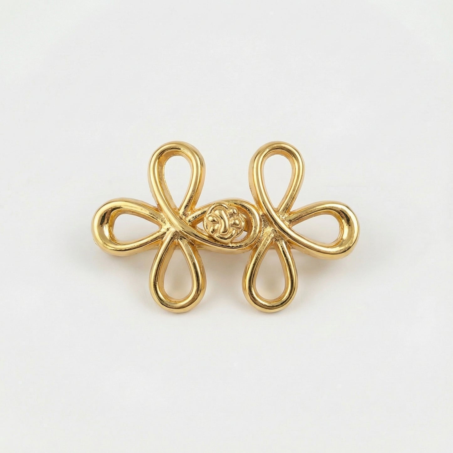 Gold bow-shaped brooch on a light gray background