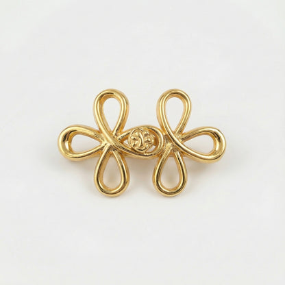 Gold bow-shaped brooch on a light gray background