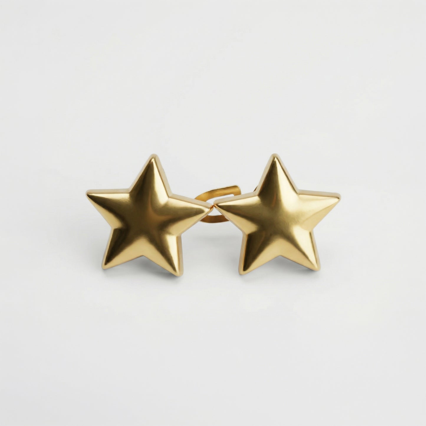 Gold star-shaped earrings on a light gray background
