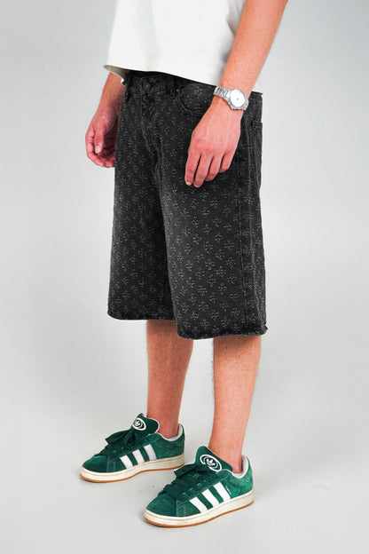 Person wearing black shorts and green Adidas sneakers on a plain background