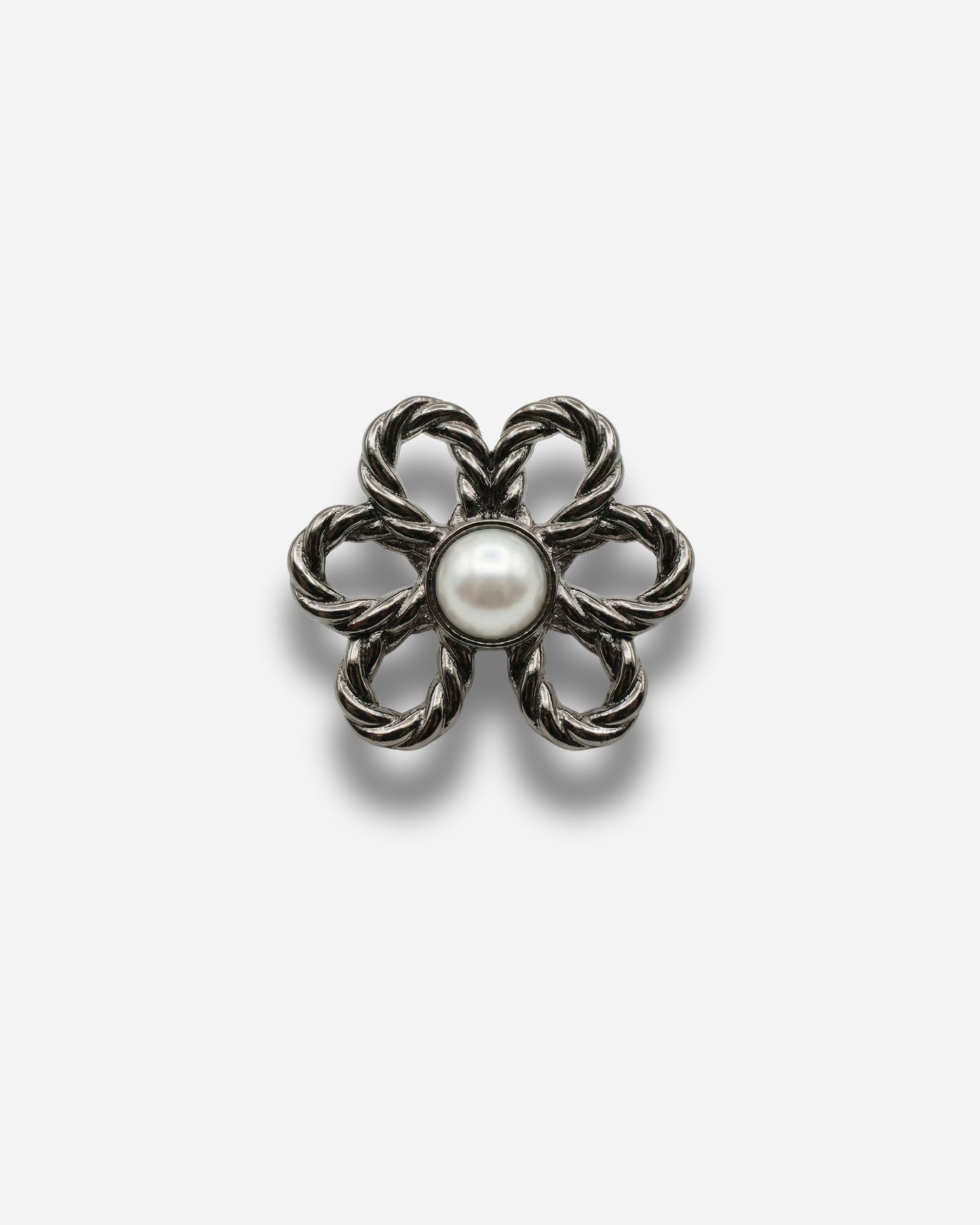 Flower-shaped brooch with a central pearl on a plain background.
