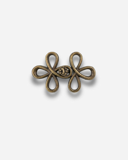 Bronze decorative clasp with a floral design on a plain background.