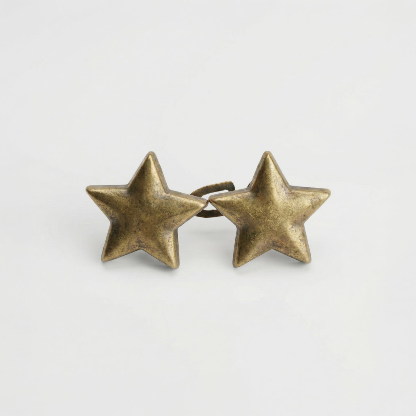 Pair of brass star-shaped earrings on a light gray background
