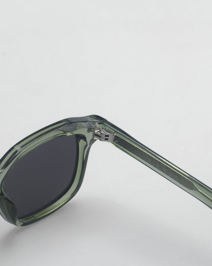 Close-up of green sunglasses with dark lenses and patterned temple on a plain background.