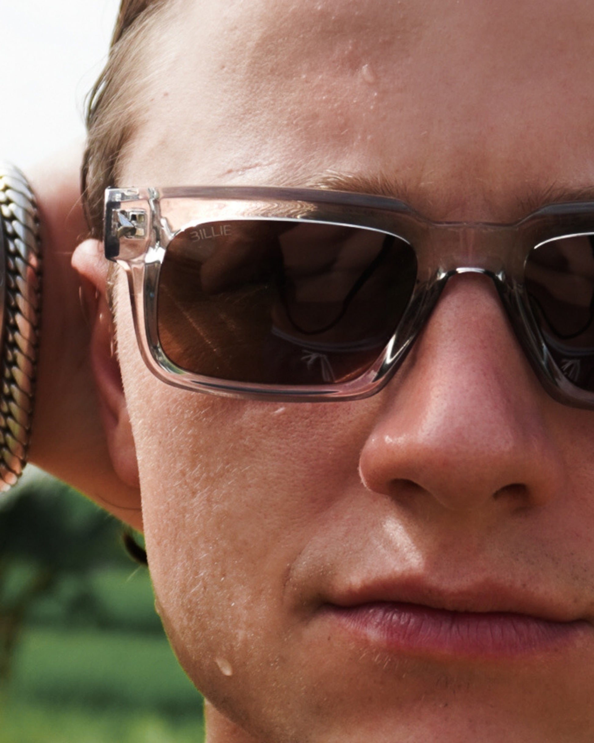 Close-up of a person wearing sunglasses with clear frames and dark lenses.