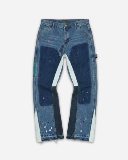 Patchwork jeans with various shades of blue and paint splatters, displayed on a plain background.