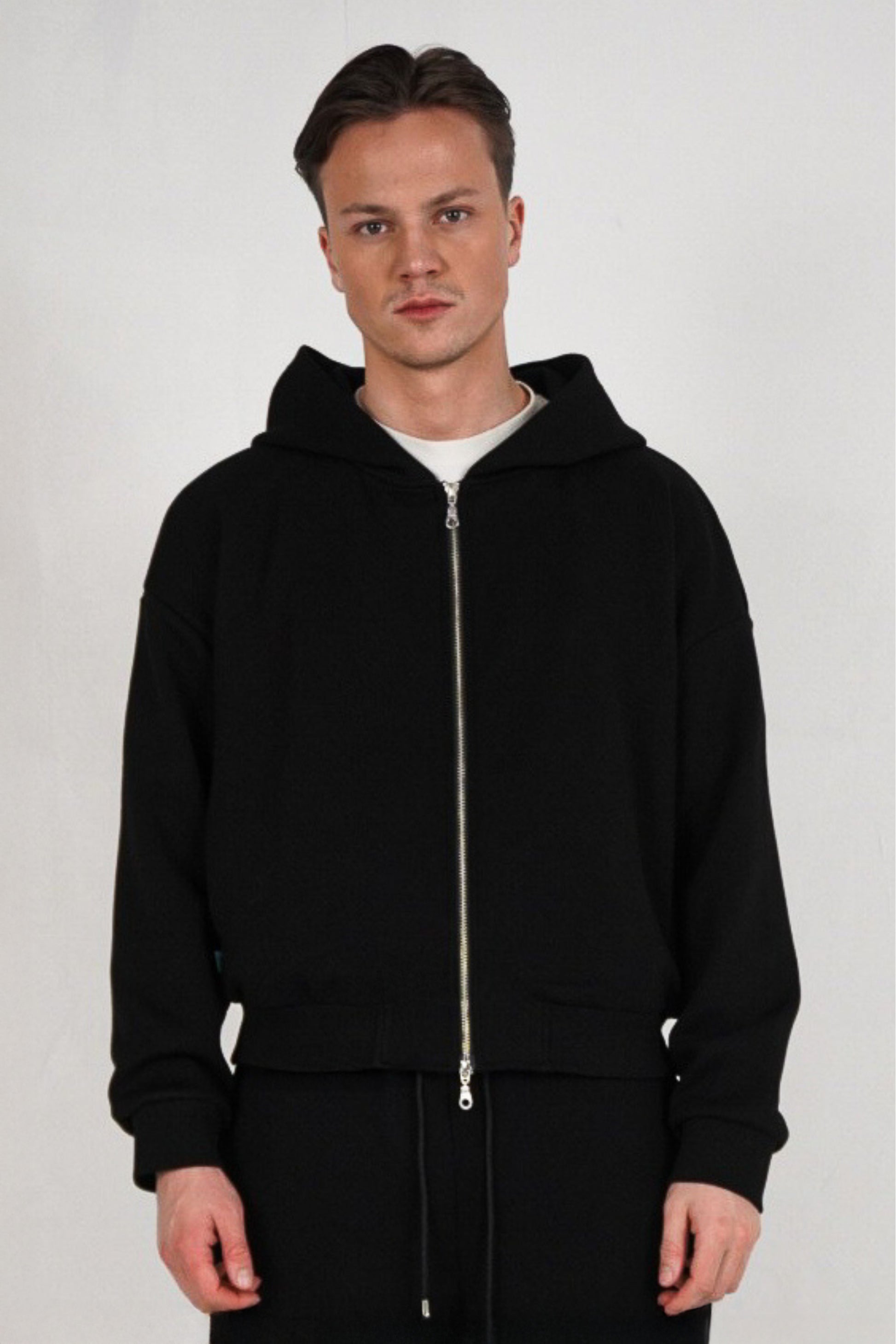 Man wearing a black hoodie on a plain background